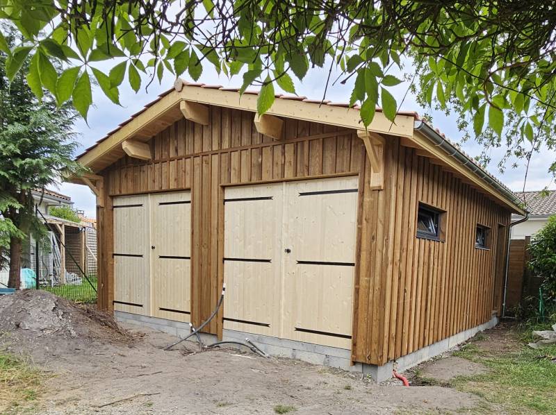 Vue de face du garage bois sur mesure réalisé par LSM Menuiserie, avec bardage volige et couvre-joint.
