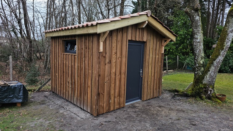 Abri de jardin 9m2 en ossature bois avec bardage volige et couvre-joint à Saint-Jean-d’Illac, finition traditionnelle et intégration paysagère soignée.
