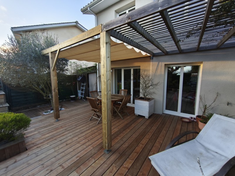 Pergola bois avec store rétractable coulissant installée dans un jardin à Arès proche du Bassin d’Arcachon.