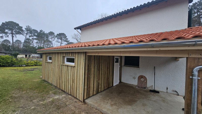 Garage attenant en ossature bois à Martignas-sur-Jalle avec toiture mono pente, bardage volige verticale et couvre-joint, parfaitement intégré à la façade existante.